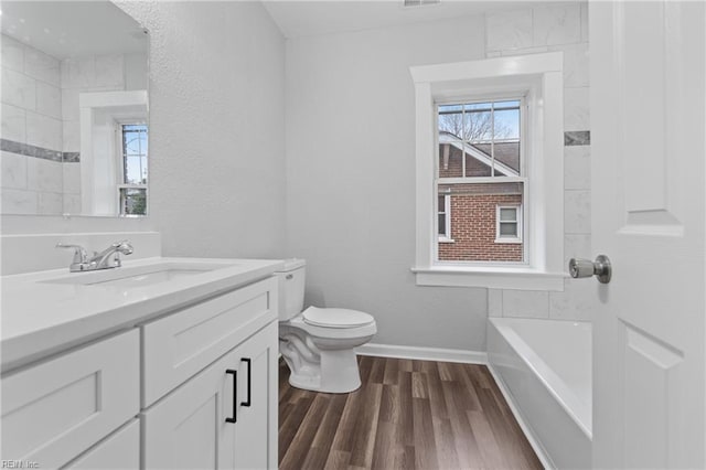 bathroom with hardwood / wood-style flooring, vanity, toilet, and a washtub