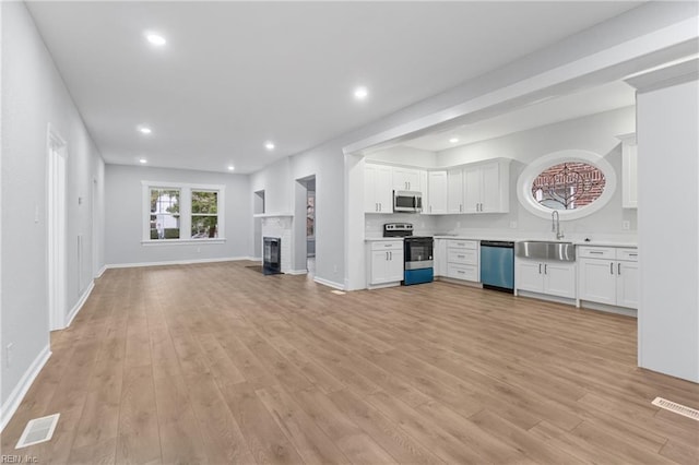 kitchen featuring white cabinetry, appliances with stainless steel finishes, sink, and light hardwood / wood-style flooring