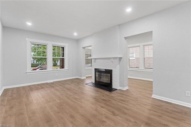 unfurnished living room featuring a healthy amount of sunlight, a fireplace, and light hardwood / wood-style floors