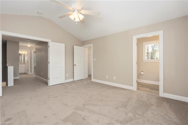 unfurnished bedroom with lofted ceiling, light colored carpet, connected bathroom, and ceiling fan