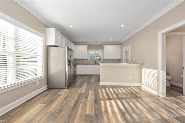 kitchen with sink, white cabinetry, light stone counters, ornamental molding, and stainless steel appliances