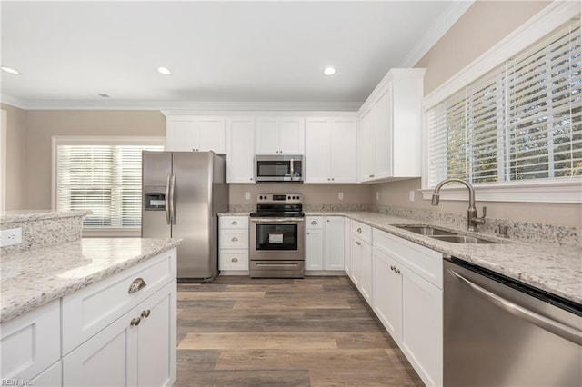 kitchen with sink, crown molding, light stone counters, appliances with stainless steel finishes, and white cabinets