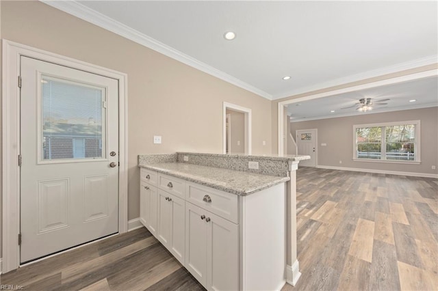 kitchen featuring white cabinetry, crown molding, kitchen peninsula, light stone countertops, and light hardwood / wood-style floors