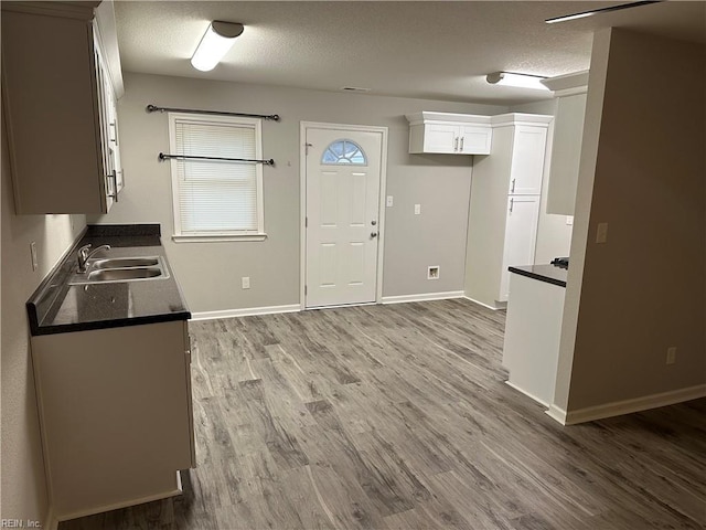 kitchen featuring white cabinetry, sink, hardwood / wood-style floors, and a textured ceiling