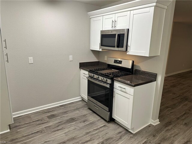 kitchen with white cabinetry, stainless steel appliances, and dark hardwood / wood-style floors