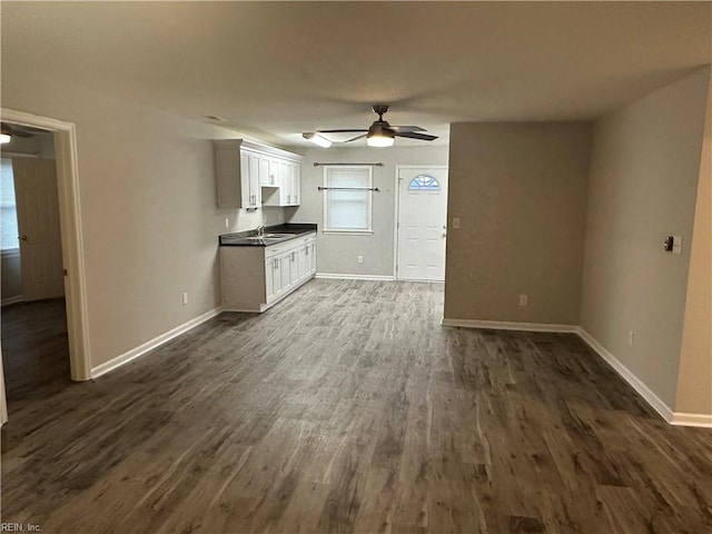 unfurnished living room with ceiling fan, sink, and dark hardwood / wood-style floors