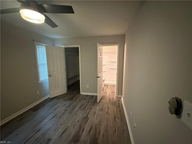 unfurnished bedroom with ceiling fan, a spacious closet, dark hardwood / wood-style floors, and a closet