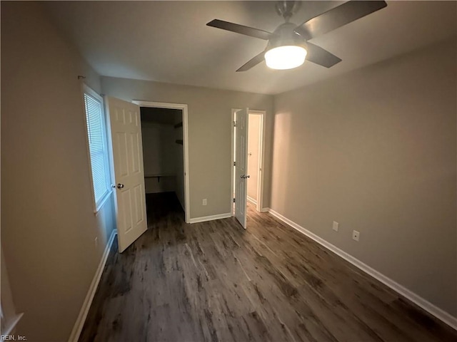 unfurnished bedroom with ceiling fan, dark hardwood / wood-style flooring, a closet, and a spacious closet