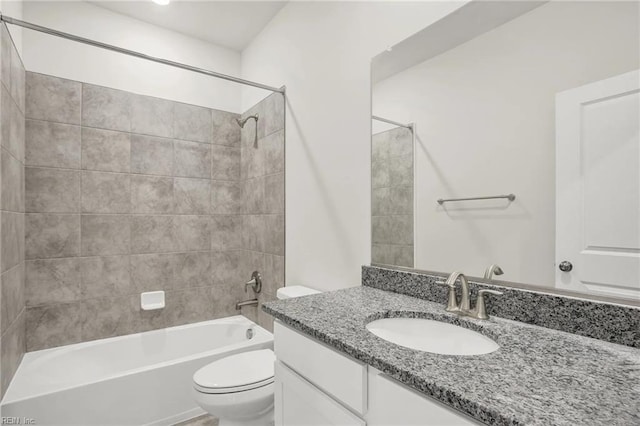 full bathroom featuring vanity, tiled shower / bath combo, and toilet