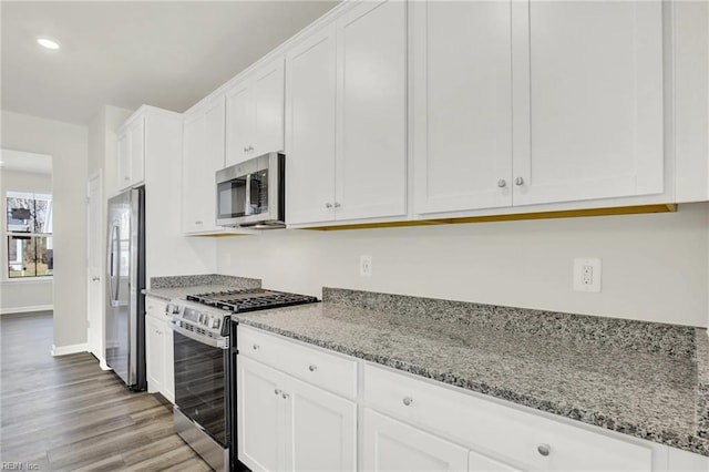 kitchen with white cabinetry, light stone countertops, light hardwood / wood-style floors, and appliances with stainless steel finishes