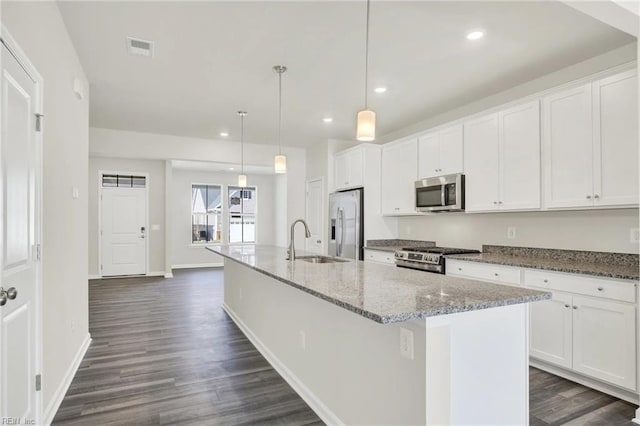 kitchen with decorative light fixtures, an island with sink, sink, white cabinets, and stainless steel appliances