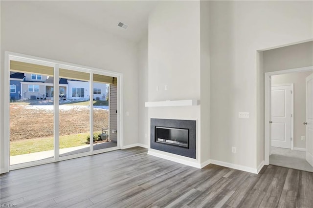 unfurnished living room featuring hardwood / wood-style flooring and a towering ceiling