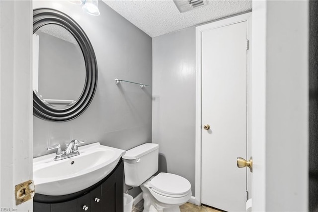 bathroom featuring vanity, toilet, and a textured ceiling