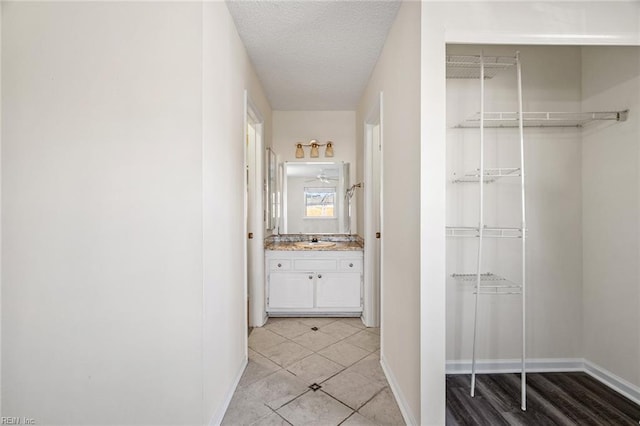 corridor featuring sink, a textured ceiling, and light tile patterned floors