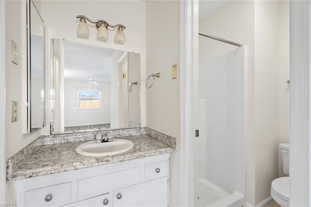 bathroom featuring toilet, vanity, ceiling fan, and walk in shower