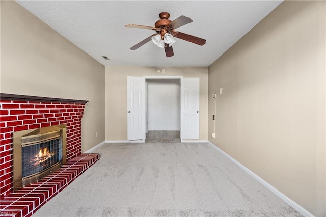 unfurnished living room featuring ceiling fan, a fireplace, and carpet