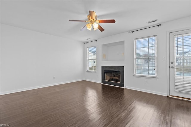 unfurnished living room featuring dark hardwood / wood-style floors, a wealth of natural light, and ceiling fan