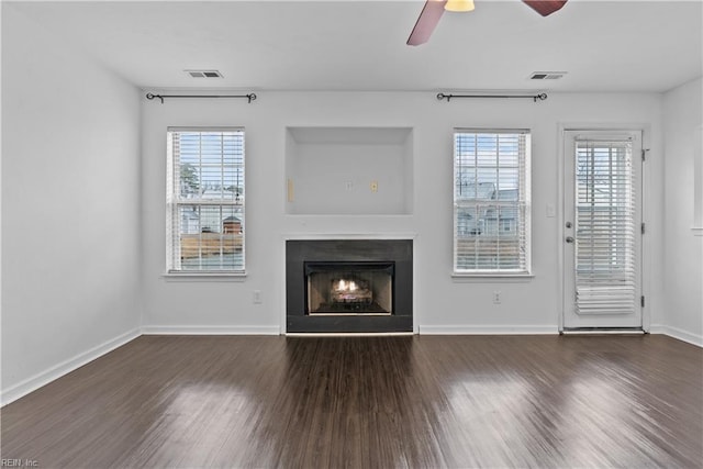 unfurnished living room featuring dark hardwood / wood-style flooring, plenty of natural light, and ceiling fan