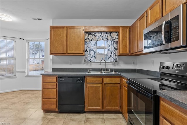 kitchen with sink, light tile patterned floors, and black appliances