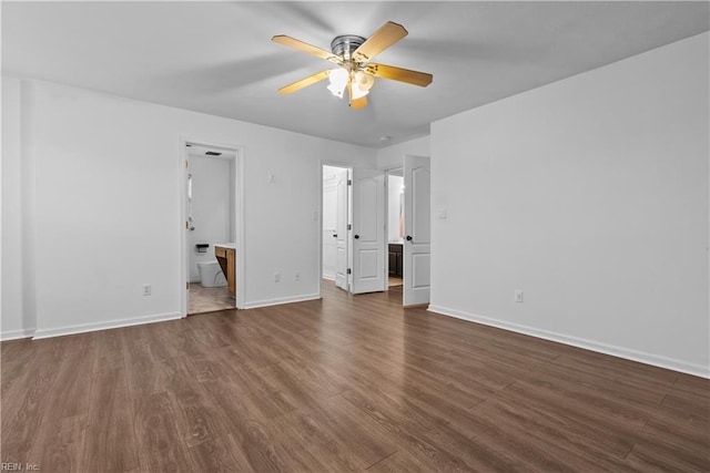 unfurnished bedroom featuring ensuite bath, dark wood-type flooring, and ceiling fan