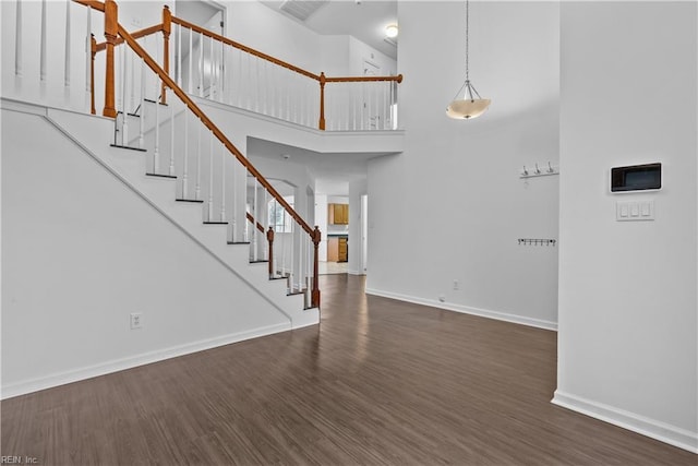 interior space featuring a towering ceiling and dark hardwood / wood-style floors