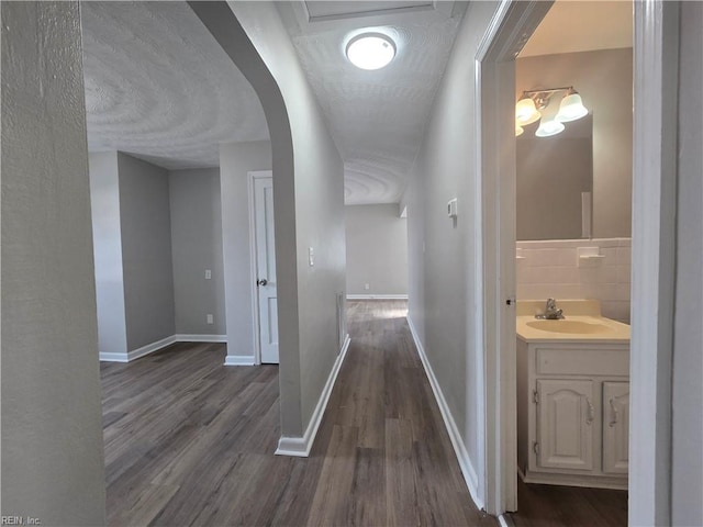 corridor featuring dark hardwood / wood-style flooring, sink, and a textured ceiling