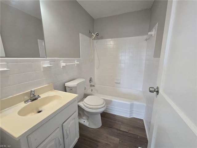 full bathroom featuring tile walls, tiled shower / bath combo, vanity, hardwood / wood-style flooring, and toilet