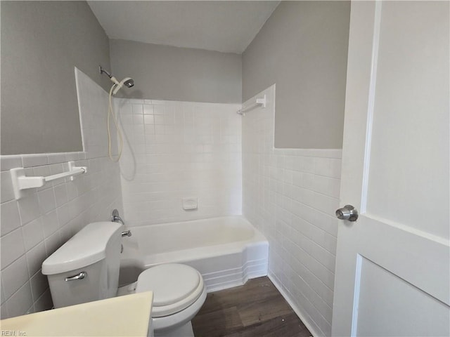 bathroom with hardwood / wood-style flooring, tiled shower / bath, toilet, and tile walls