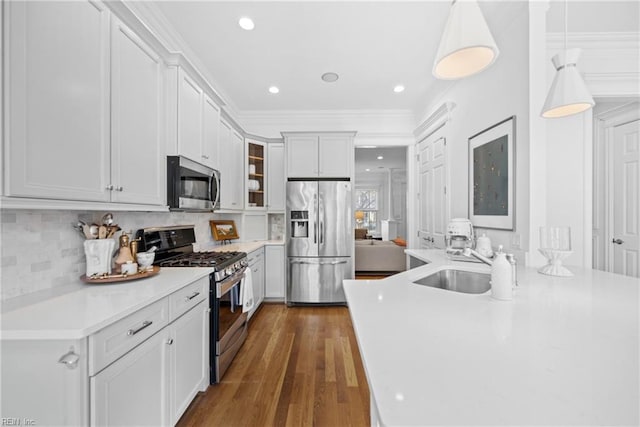 kitchen featuring crown molding, stainless steel appliances, hanging light fixtures, and white cabinets