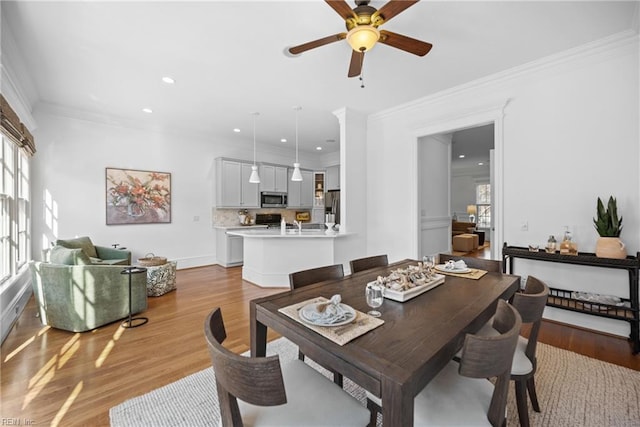 dining room featuring crown molding, ceiling fan, plenty of natural light, and light hardwood / wood-style flooring