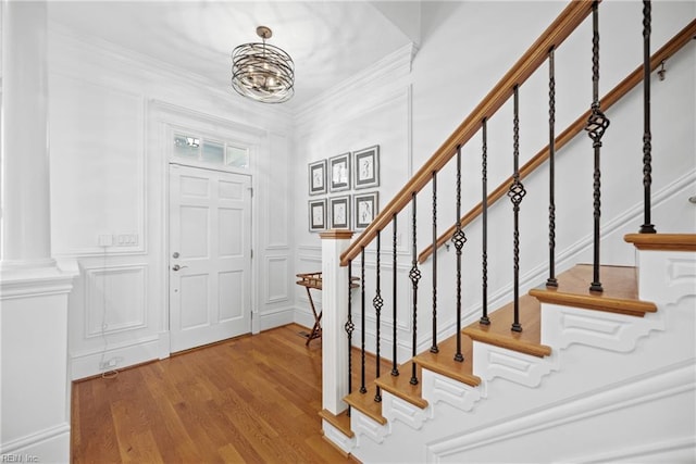 entrance foyer with wood-type flooring, a chandelier, and crown molding