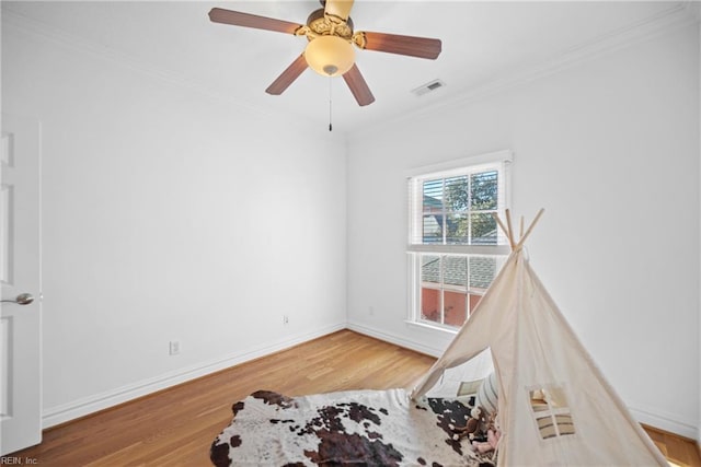 interior space featuring wood-type flooring, ornamental molding, and ceiling fan