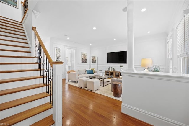 living room with crown molding, wood-type flooring, and ornate columns