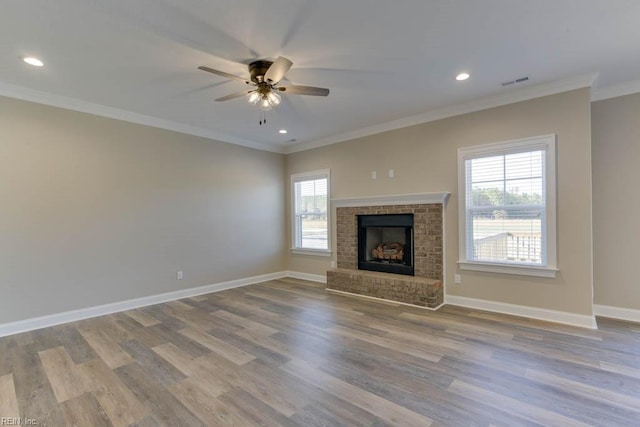 unfurnished living room featuring ornamental molding, plenty of natural light, a fireplace, and light hardwood / wood-style flooring