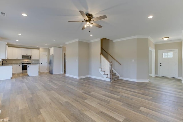 unfurnished living room featuring ornamental molding, sink, ceiling fan, and light hardwood / wood-style floors