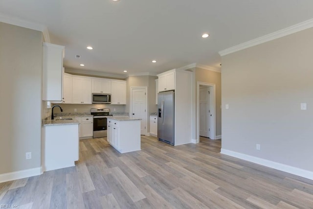 kitchen featuring a kitchen island, appliances with stainless steel finishes, white cabinetry, sink, and light hardwood / wood-style flooring