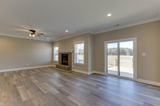 unfurnished living room with a brick fireplace, hardwood / wood-style flooring, ornamental molding, and ceiling fan