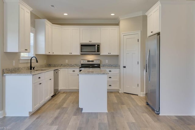 kitchen with light stone counters, sink, a center island, and appliances with stainless steel finishes