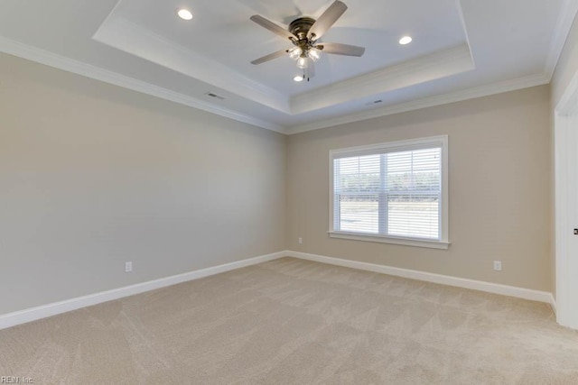 carpeted spare room featuring a raised ceiling, ornamental molding, and ceiling fan