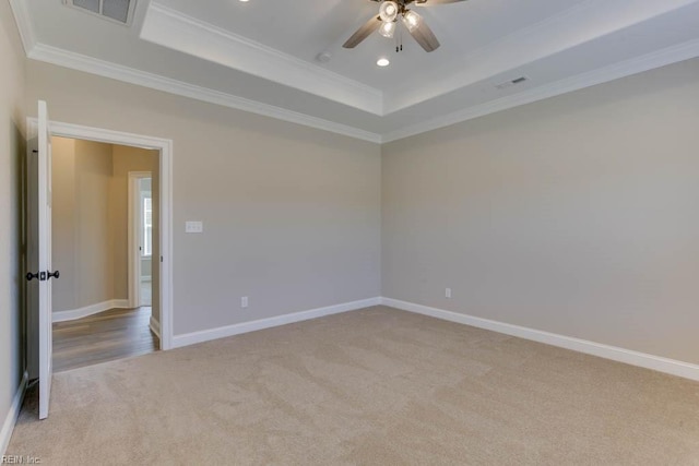 spare room featuring crown molding, ceiling fan, a tray ceiling, and light carpet