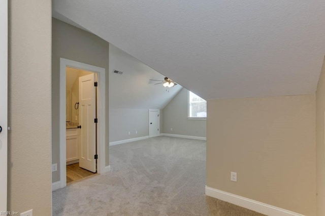 additional living space with ceiling fan, lofted ceiling, light carpet, and a textured ceiling