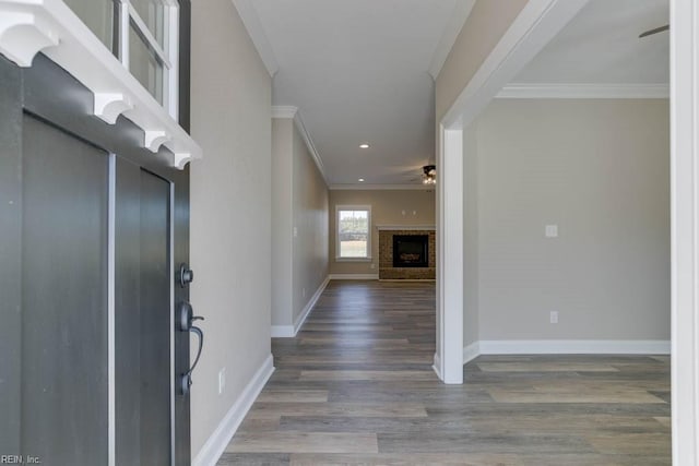 foyer entrance with hardwood / wood-style flooring, ornamental molding, a brick fireplace, and ceiling fan