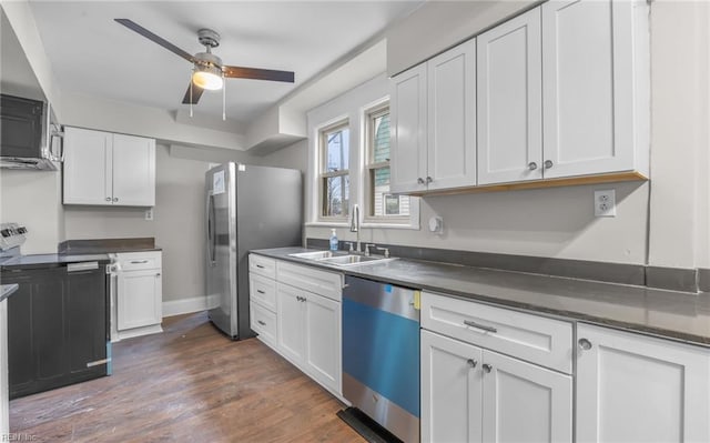 kitchen with appliances with stainless steel finishes, dark hardwood / wood-style floors, sink, and white cabinets