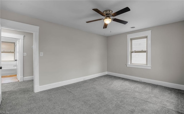 carpeted spare room featuring ceiling fan, visible vents, and baseboards