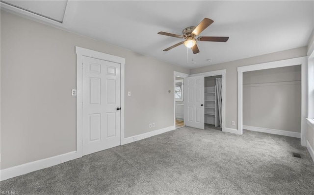 unfurnished bedroom with two closets, a ceiling fan, baseboards, and carpet flooring