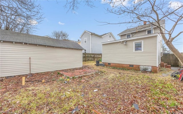 rear view of house featuring crawl space and fence