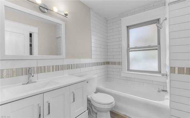 full bathroom with toilet, tile walls, vanity, and shower / bathtub combination