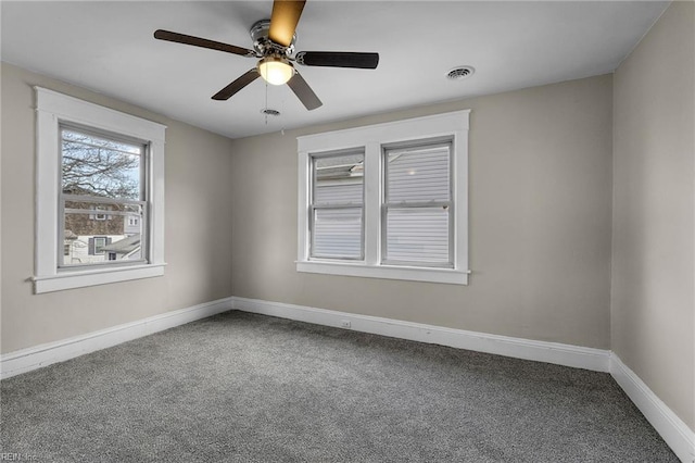 empty room with carpet floors, visible vents, baseboards, and ceiling fan