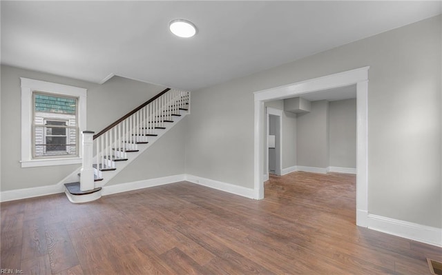 spare room with stairway, dark wood finished floors, visible vents, and baseboards