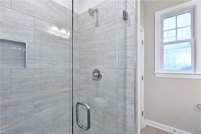 bathroom with baseboards, a shower stall, and plenty of natural light